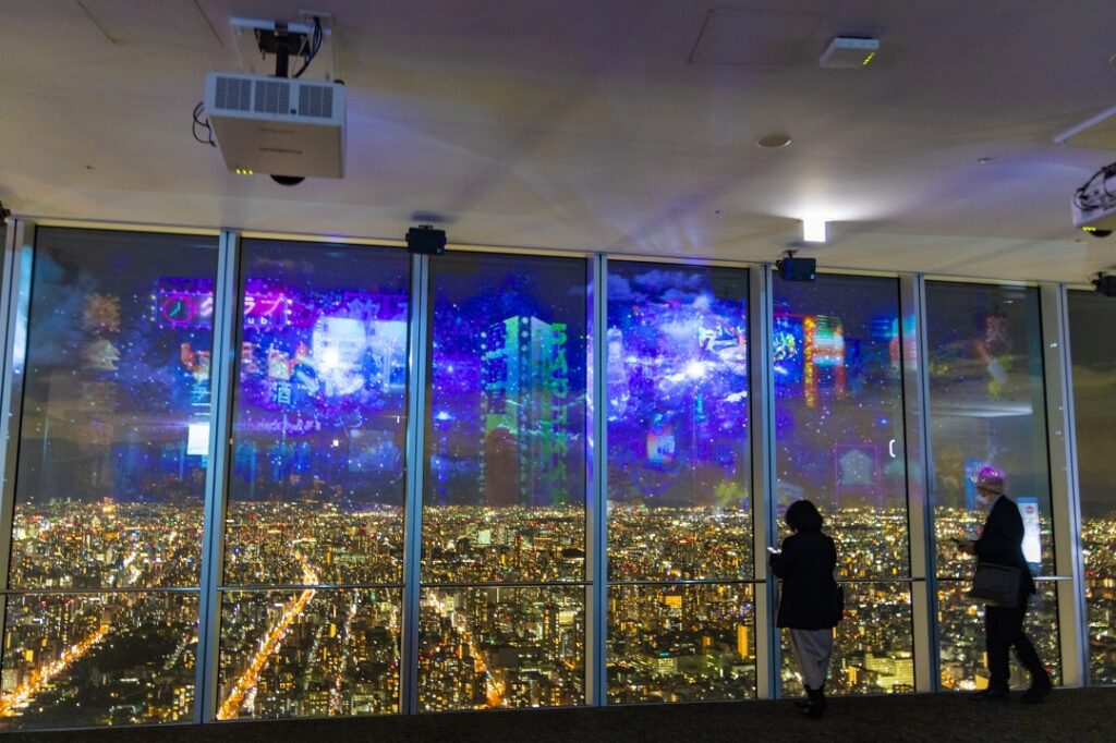 하루카스 300 전망대에서 오사카 야경. 사람들이 야경을 내려다 보고 있다.